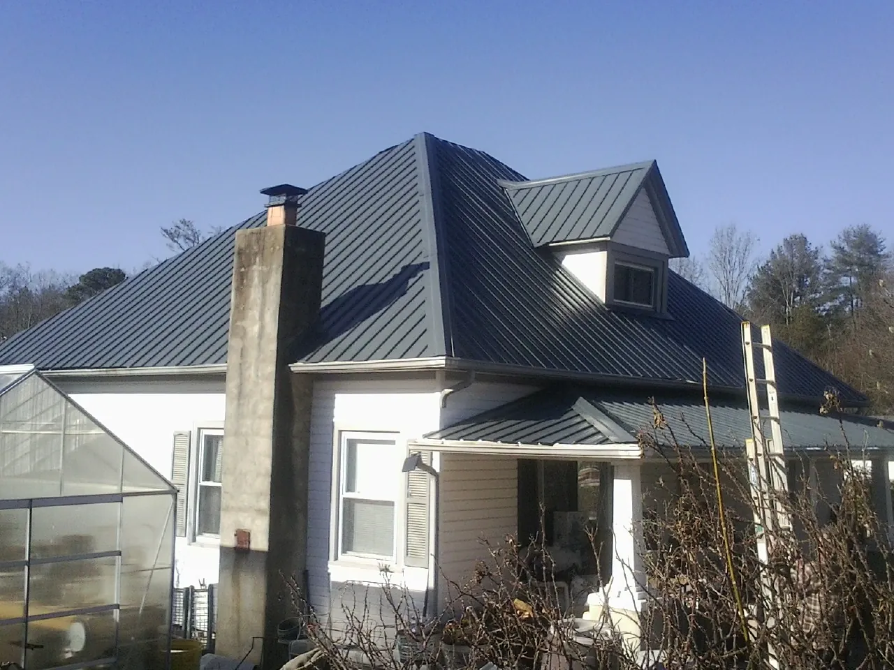 Dark blue standing seam metal roof on a white farmhouse with dormer — Slate & Tile Roof Repair by Roofing Brothers in Cranbury