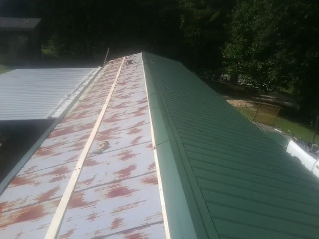 Old rusted panels beside newly installed green metal roofing — Wind Damage Roof Repair by Roofing Brothers in Cranbury