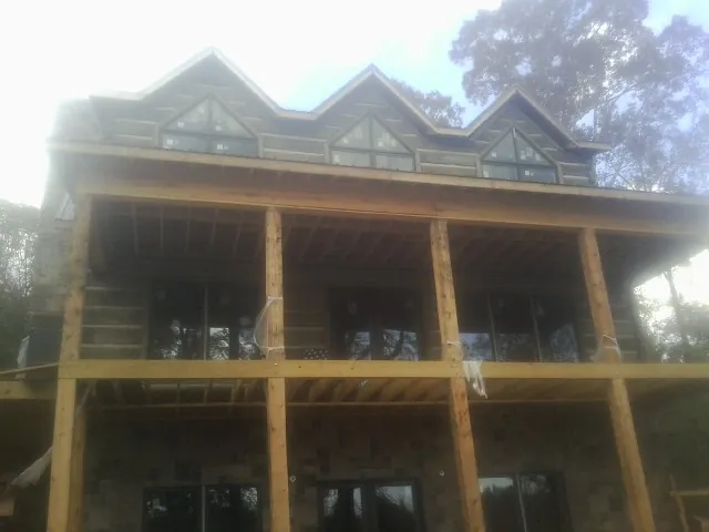 Dormers and porch framing on a large log home under construction — Roof Coating work by our crew in Cranbury