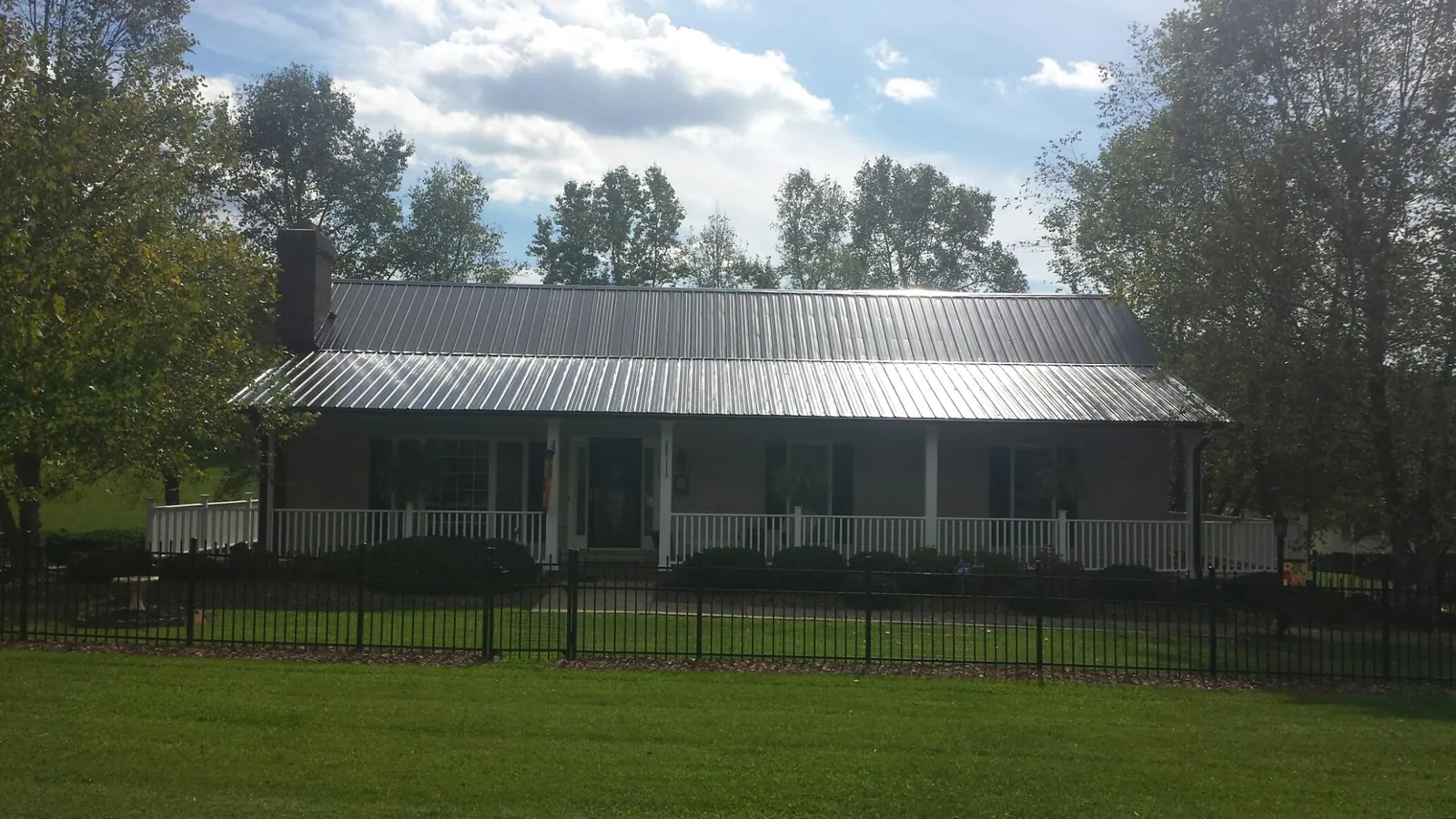 Gray metal roof on a brick ranch with a full width front porch — Gutter Guard Installation work by our crew in Cranbury