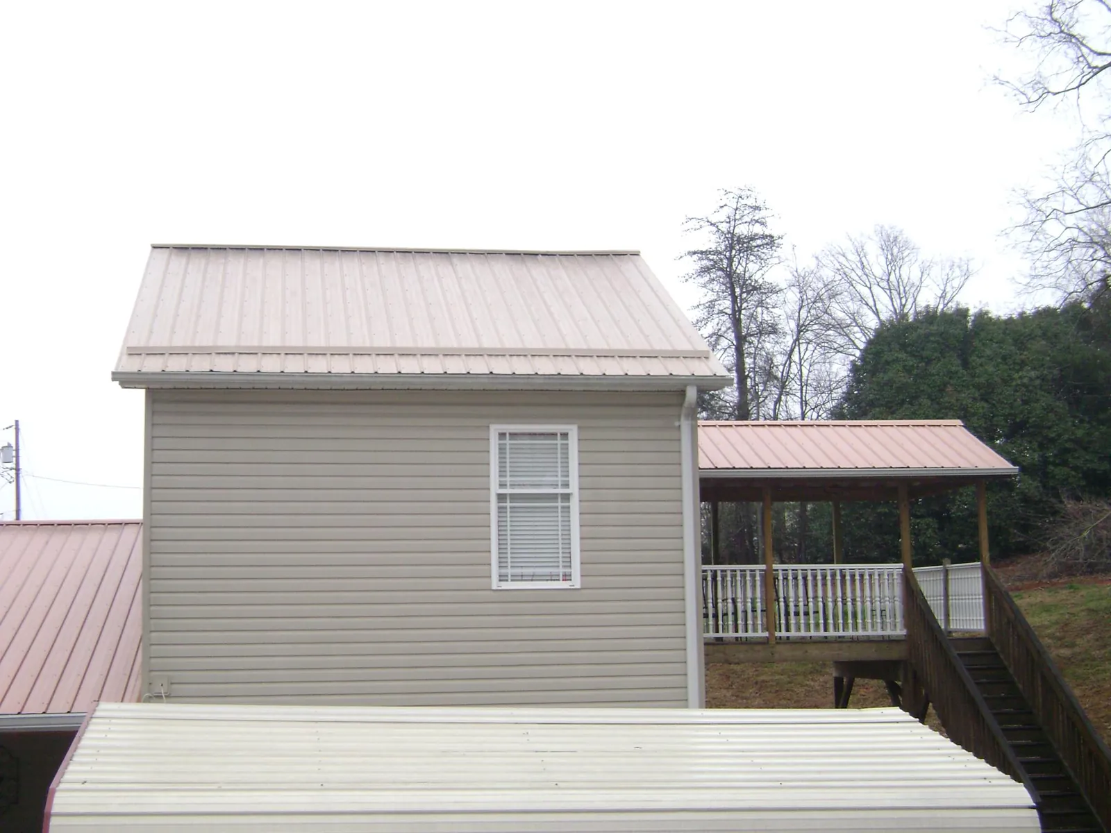 Tan metal roofs on a two story addition and attached porch, from a Roof Replacement job in Cranbury