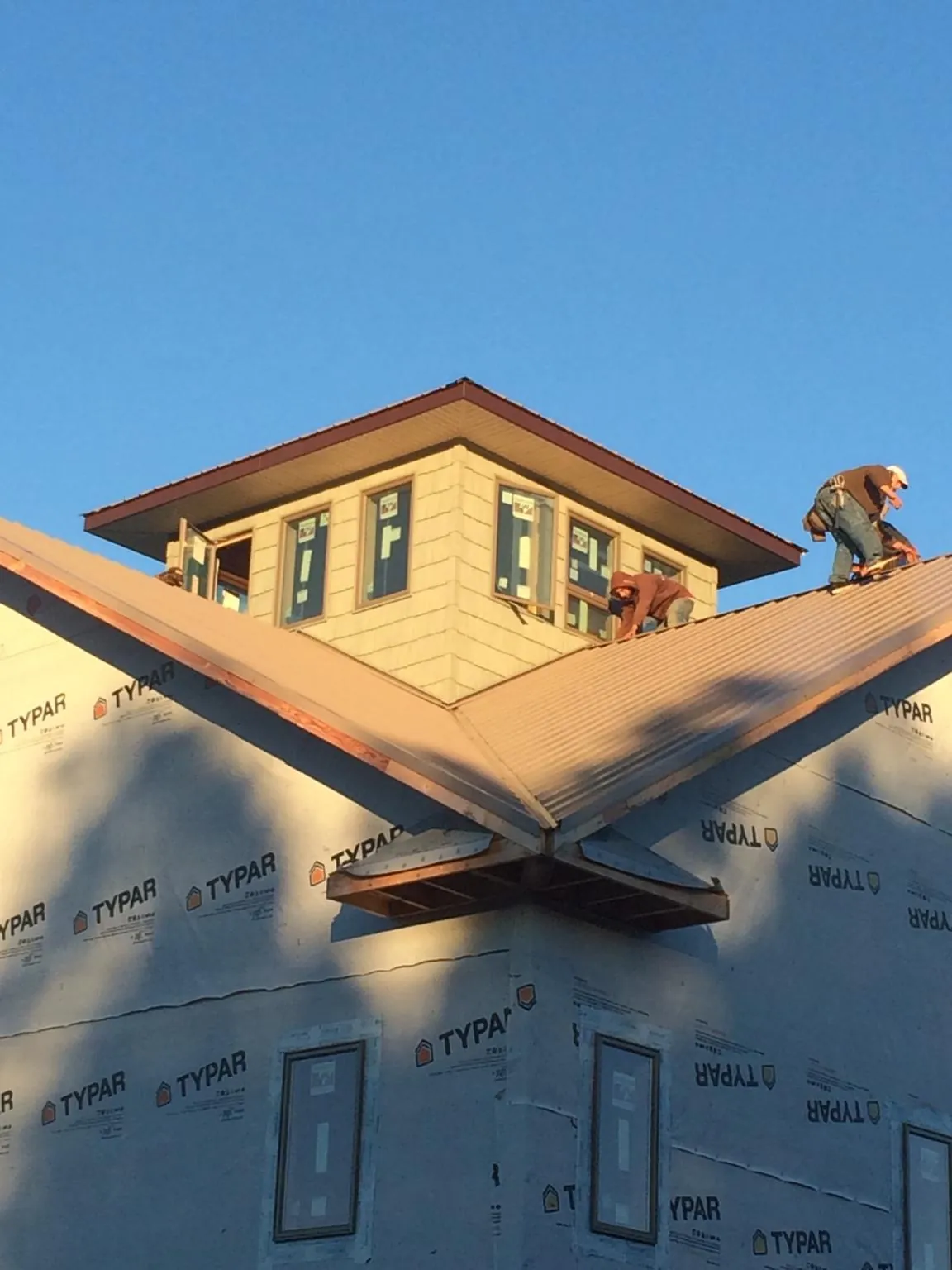 Roofers working around a rooftop cupola on a new metal roof at sunset — Roof Waterproofing in Cranbury by Roofing Brothers